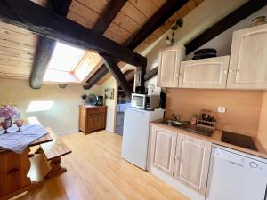 eine Küche mit einem weißen Kühlschrank und einem Tisch in der Unterkunft Charmant studio dans ferme avec terrasse et parking - montagnes des Vosges - FR-1-589-164 in Le Ménil