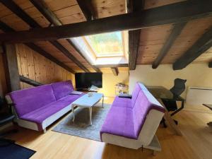 uma sala de estar com um sofá roxo e uma mesa em Gîte Le Menil, 1 pièce, 2 personnes - FR-1-589-164 em Le Ménil