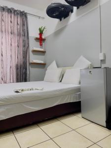 a bed with white pillows and a refrigerator in a room at Sunrise Guest Inn in Pretoria