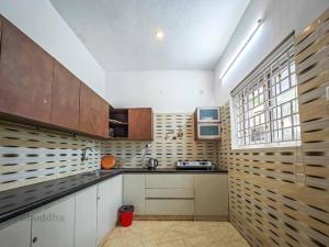 a kitchen with white cabinets and wooden walls at Royal Experiences Buddha Sea View Villa, Mutukadu Beach ECR Chennai in Chennai