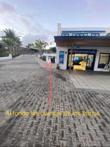 a building with a red arrow on a street at Barco Princess Cachucho Fly in Puerto Calero