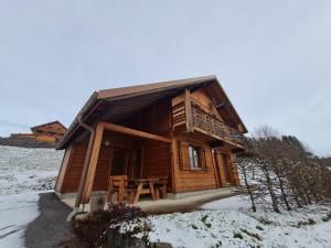 a log cabin in the snow with a table at Chalet chaleureux face aux pistes, proche Gérardmer, idéal pour famille, balcon et terrasse - FR-1-589-182 in Ban-sur-Meurthe-Clefcy