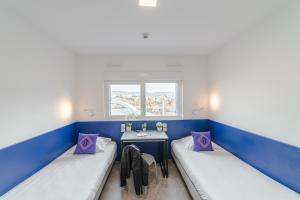 2 Betten in einem Zimmer mit einem Tisch und einem Fenster in der Unterkunft Montempô Marseille Centre Dôme in Marseille