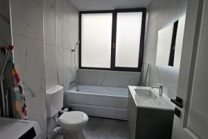 een badkamer met een bad, een toilet en een wastafel bij Nordic Residence 5 in Suceava