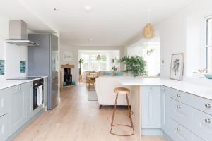 a kitchen with white cabinets and a white counter top at Mariners: Stylish Beachside Getaway with Sea Views in East Wittering