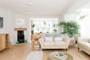 a living room with white furniture and a fireplace at Mariners: Stylish Beachside Getaway with Sea Views in East Wittering