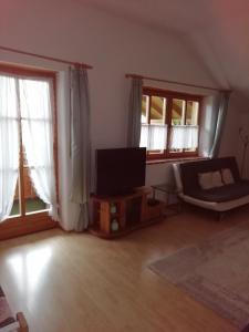 a living room with a flat screen tv and two windows at Haus Hiebl in Teisendorf