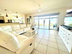 uma sala de estar com um sofá branco e uma cozinha em Incredible beachfront home, 10 min to Port Douglas - Diamond Cliff em Mowbray