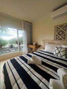 um quarto com uma grande cama listrada e uma janela em Incredible beachfront home, 10 min to Port Douglas - Diamond Cliff em Mowbray
