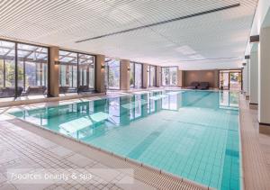 a large swimming pool with green tiles in a building at Lenkerhof gourmet spa resort - Relais & Châteaux in Lenk