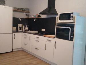 a kitchen with white cabinets and a microwave at Gîte Plombières-les-Bains, 2 pièces, 2 personnes - FR-1-589-289 in Plombières-les-Bains