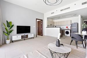 sala de estar con TV de pantalla plana y mesa en Silkhaus New 1BDR at Najmat Near Reem Central Park, en Abu Dabi