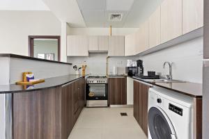 een keuken met een fornuis en een wasmachine bij Silkhaus 1BDR at Najmat Near Reem Central Park in Abu Dhabi