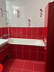 a red and white bathroom with a tub and a sink at Dristor Residence in Bucharest