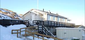 ein Haus im Schnee neben einem Zaun in der Unterkunft Ilulissat Hostel in Ilulissat
