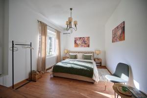 1 dormitorio blanco con 1 cama y 1 silla en Čudesni drvored, en Kikinda