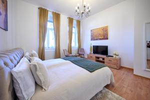 a bedroom with a white bed and a television at Čudesni drvored in Kikinda