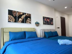 Cozy couple apartment suite في ماساي: سريرين في غرفة نوم مع ملايات زرقاء وصور على الحائط
