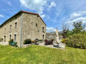 un vecchio edificio in pietra con tavolo e ombrellone di Maison de charme en Margeride: terrasse, terrain clos, proche Saugues et chemin St-Jacques - FR-1-582-146 a Saugues