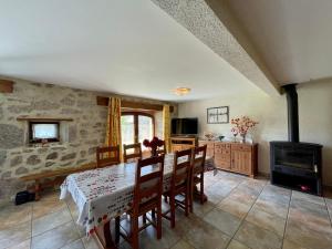 una sala da pranzo con tavolo e stufa a legna di Maison de charme en Margeride: terrasse, terrain clos, proche Saugues et chemin St-Jacques - FR-1-582-146 a Saugues