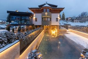 a building with a swimming pool in the snow at Hotel Nordik in Andalo