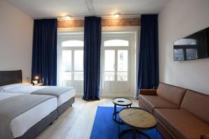マドリードにあるroom00 Gran Vía Hostelのベッドとソファのあるホテルの部屋