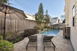 a patio with two chairs and an umbrella and a pool at Cozy and Roomy Home with Private Pool in Houston