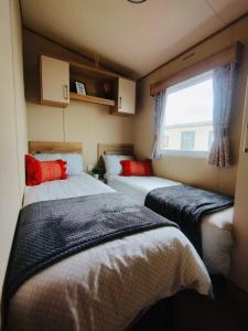 two beds in a small room with a window at 32 Holiday Resort Unity in Brean
