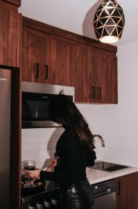 a woman standing in a kitchen with a glass of wine at Suite 208 - Destination Mont-Orford in Magog-Orford