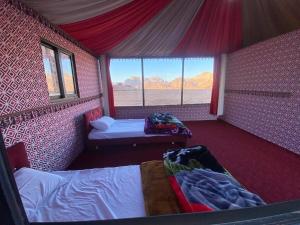 a bedroom with two beds and a window with mountains at Milky Way Nights Camp in Wadi Rum