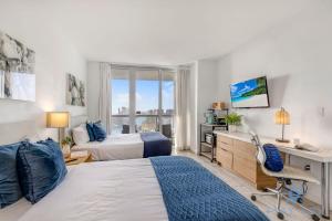 a bedroom with two beds and a desk and a desk at Upper studio Balcony Pool Gym - Near Beach in Hallandale Beach