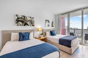 two beds in a room with a window at Upper studio Balcony Pool Gym - Near Beach in Hallandale Beach +39 photos
