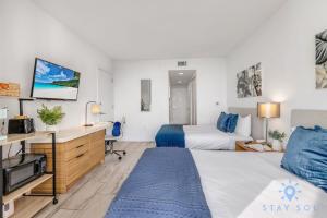 a hotel room with a bed and a desk and a tv at Upper studio Balcony Pool Gym - Near Beach in Hallandale Beach