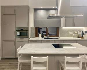 a kitchen with white cabinets and a white table and chairs at Viasavona46 Nel cuore delle Langhe in Treiso