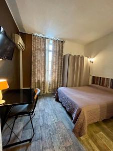 a bedroom with a bed and a desk and a window at Hotel Alexander in Perpignan