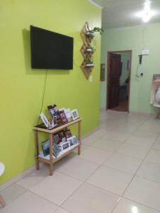 een kamer met een televisie aan een groene muur bij Casa Parintins in Parintins