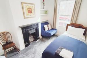 a bedroom with a bed and a chair and a fireplace at CNTRL Reading Modernized 3 bedroom House in Reading