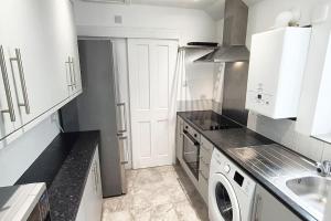 uma cozinha com uma máquina de lavar roupa e um lavatório em CNTRL Reading Modernized 3 bedroom House em Reading