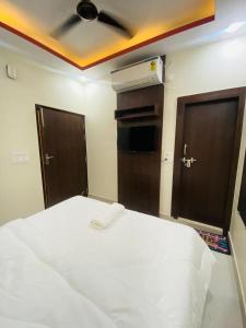 a bedroom with a bed with a ceiling fan and two doors at Hotel Pru with car parking in Alambagh