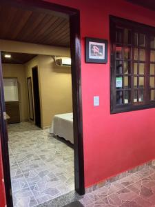 a red door leading to a room with a bed at Pousada Convés - Ilha Grande in Praia de Araçatiba
