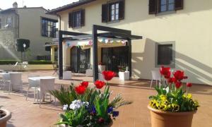 a patio with red flowers and tables and chairs at Casale dei cento Acri in Florence