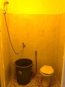 a yellow bathroom with a toilet and a bucket at Countryside Schoolstay in Takeo