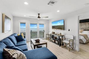 a living room with a blue couch and a bedroom at Grand Caribbean 4007 in Port Aransas