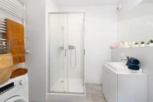 a white bathroom with a shower and a sink at Apartament Gocławska SWPS PGE Narodowy Dworzec Wschodni Soho Factory in Warsaw