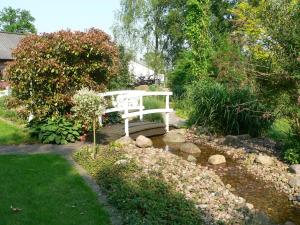 un banco blanco sentado en medio de un jardín en Landgasthaus Krimpenfort en Lohne