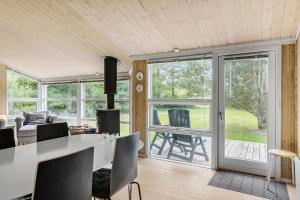 ein Wohnzimmer mit einem Tisch und Stühlen sowie Glasschiebetüren in der Unterkunft Little Fiskerbanke - Lovely, Private, And Family-friendly Holiday Home in Saltum