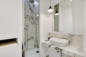 um banheiro branco com uma pia e um espelho em Pick A Flat's Apartment in Saint-Michel - Rue Pestalozzi em Paris
