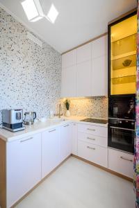 eine weiße Küche mit weißen Schränken und einer Kachelwand in der Unterkunft Mountain view apartment in Almaty