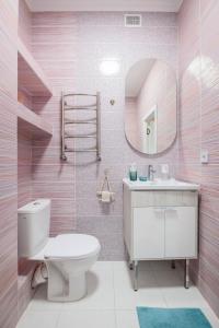 ein rosafarbenes Bad mit einem WC und einem Spiegel in der Unterkunft Mountain view apartment in Almaty