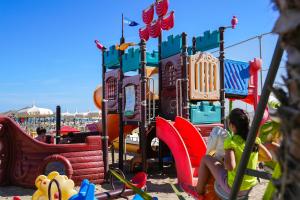 een groep kinderen die spelen in een speeltuin bij Hotel Rex in Gabicce Mare